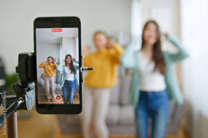 Asian young woman with her friend created her dancing video by smartphone camera together. To share video on tiktok social media application